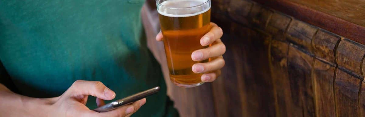 Person holding cell phone and beer