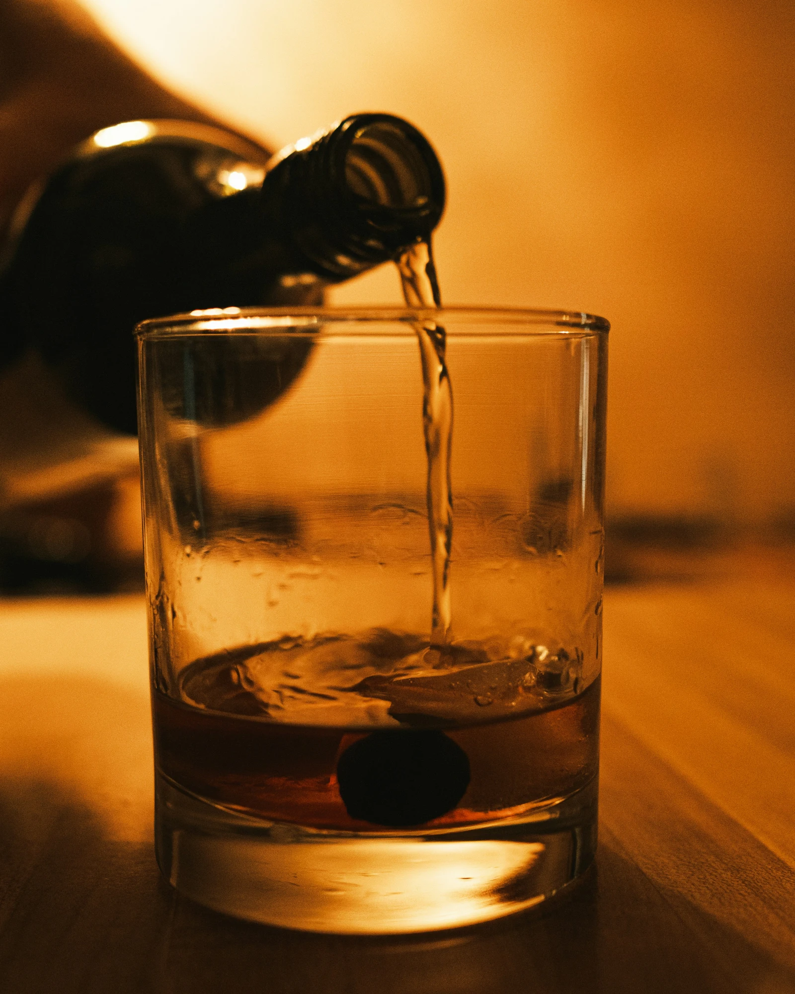 Dark bottle pouring alcohol into a glass