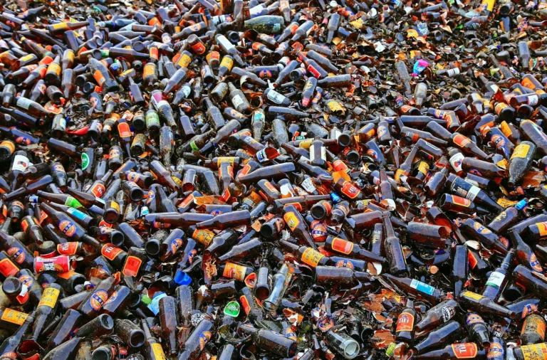 Multiple broken beer bottles on the ground represent the problems associated with alcohol dependence.